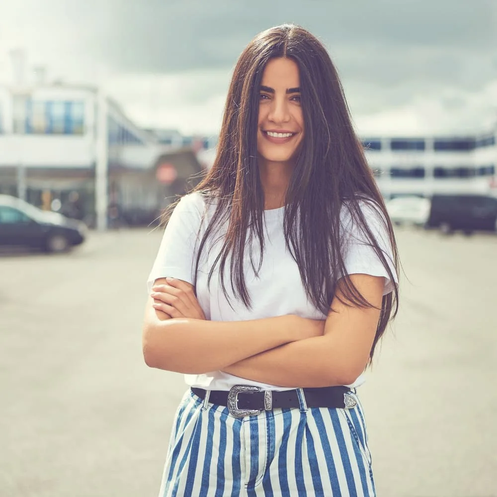 Young woman standing outdoors with arms crossed